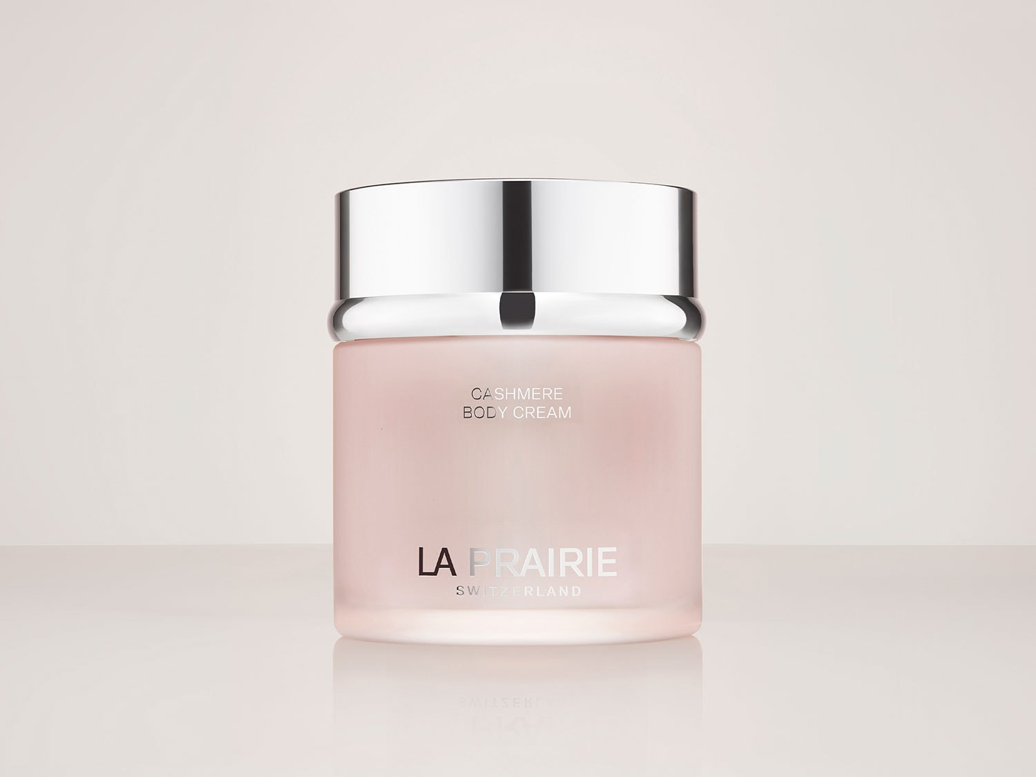 Die La Prairie Cashmere Body Cream ist in einem eleganten, milchig-rosa Tiegel mit einem glänzenden silbernen Deckel verpackt und verspricht luxuriöse Pflege für Ihre Haut.