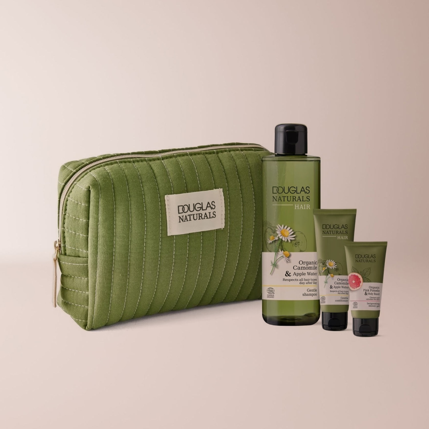 Das Douglas Naturals Set enthält eine grüne Kosmetiktasche und drei Produkte: ein Shampoo, eine Spülung und ein Duschgel, alle mit Kamille, Apfelwasser, rosa Pomelo und Heiligem Basilikum.