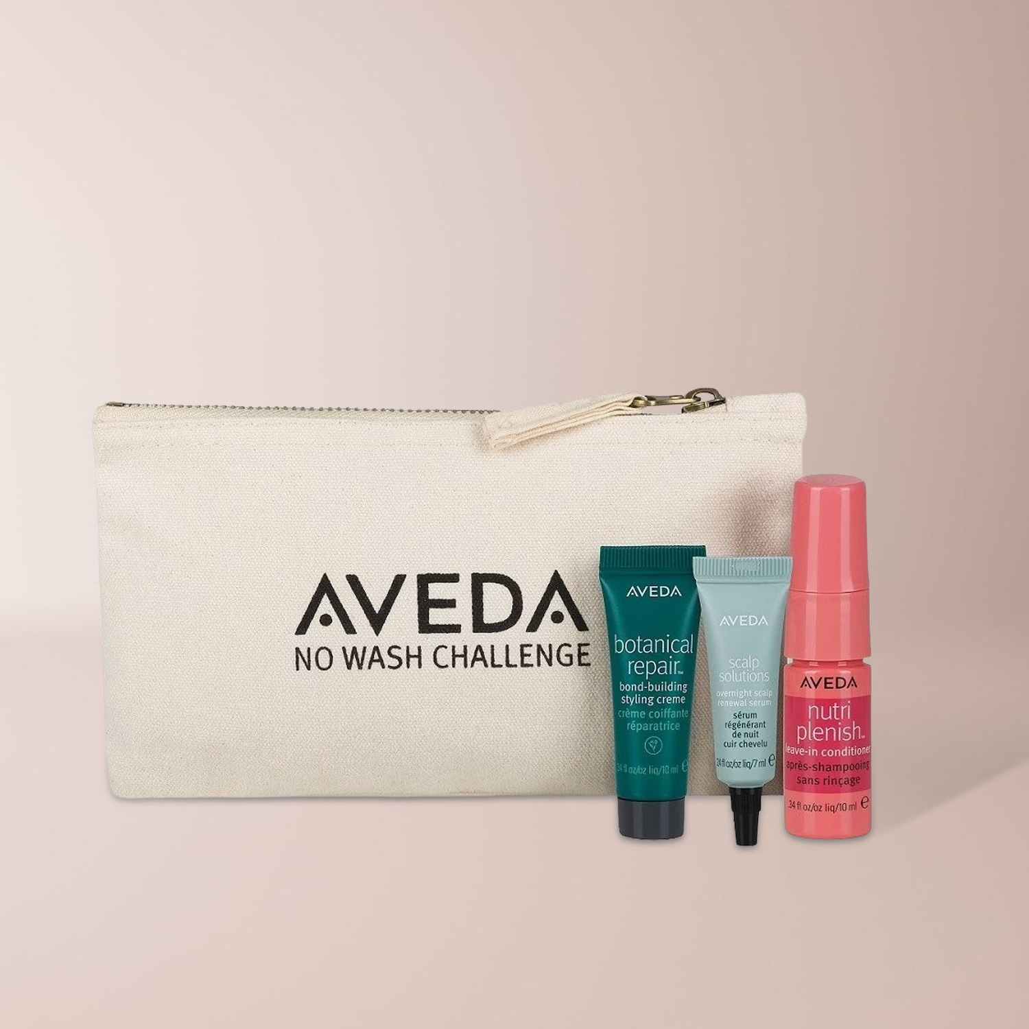 Das Aveda "No Wash Challenge" Set enthält eine cremefarbene Kosmetiktasche mit drei kleinen Produktproben: eine grüne Tube "botanical repair" Styling Creme, eine hellblaue Tube "scalp solutions" Serum und eine pinke Flasche "nutri plenish" Leave-in Conditioner.