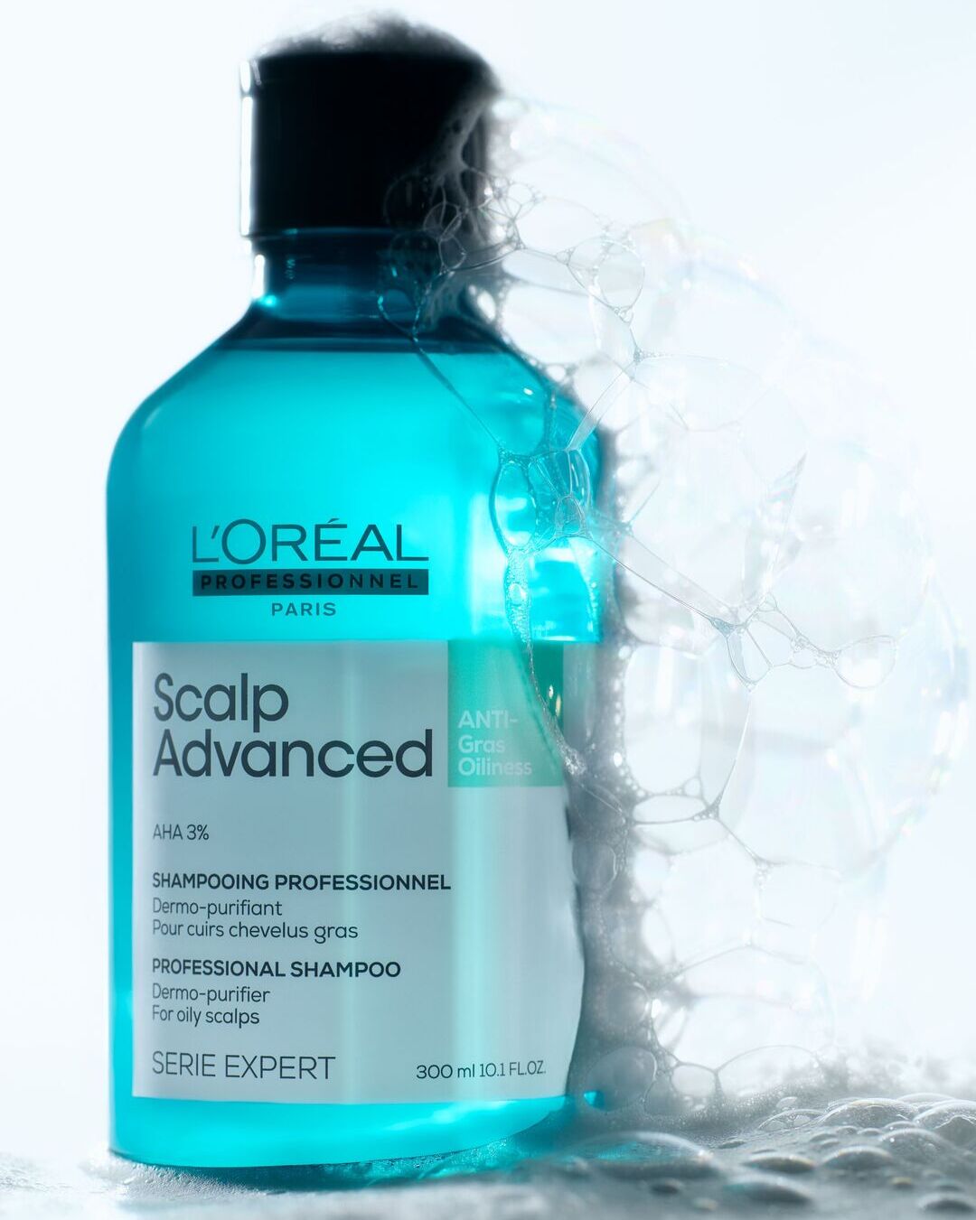 L'Oréal Professionnel Scalp Advanced šampūnas nuo riebalų, 300 ml, mėlynos spalvos buteliuke su juodu dangteliu, skirtas riebiems plaukams, su AHA 3% ir putomis aplink.