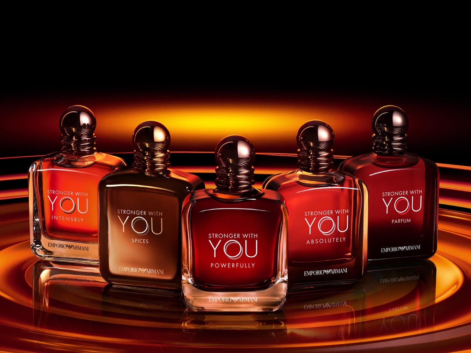 Vijf flacons van Emporio Armani's "Stronger With You" parfumlijn, elk met een unieke ondertitel zoals "Intensely", "Spices", "Powerfully", "Absolutely" en "Parfum", staan op een glanzend oppervlak met een warme oranje gloed op de achtergrond.