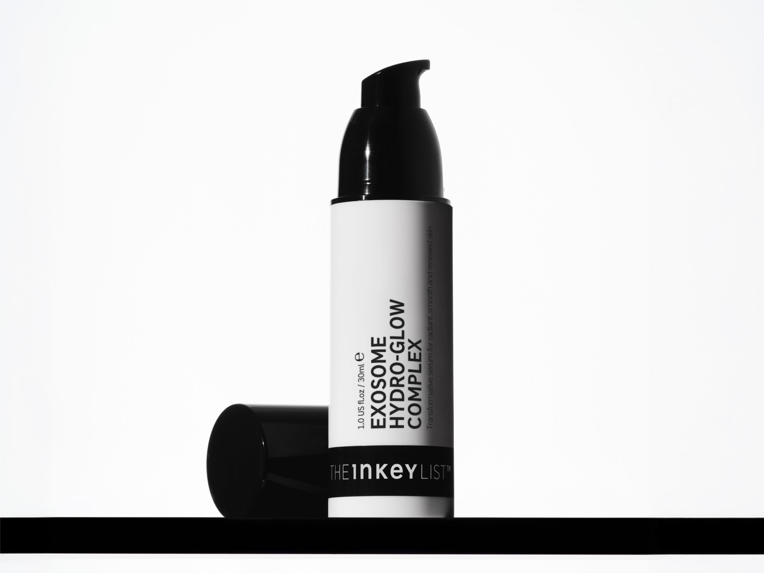 Eine weiße Flasche des Serums The Inkey List Exosome Hydro-Glow Complex mit schwarzem Spender und abgenommenem Deckel vor weißem Hintergrund.