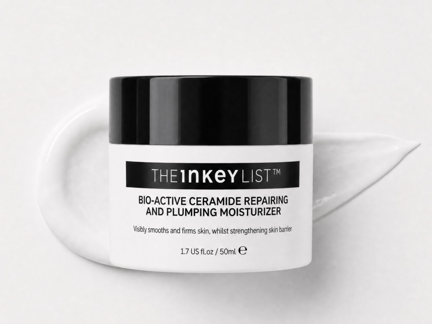 Eine weiße Dose des Bio-Active Ceramide Repairing and Plumping Moisturizers von The Inkey List mit schwarzem Deckel und schwarzer Schrift, liegt auf einem Klecks der weißen Creme auf weißem Untergrund.