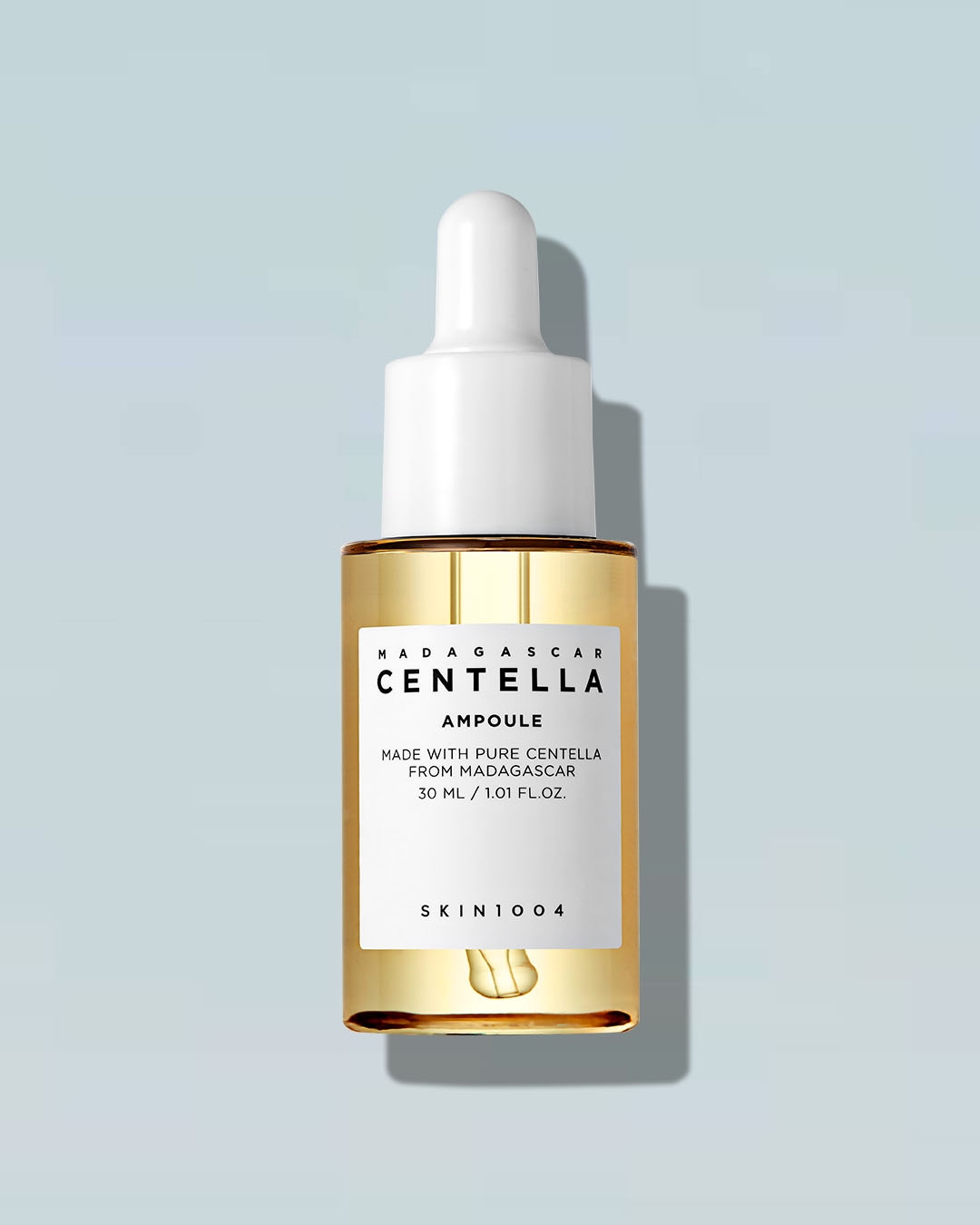 Przezroczysta buteleczka z zakraplaczem SKIN1004 Madagascar Centella Ampoule o pojemności 30 ml, wypełniona jest jasnożółtym płynem, a na białej etykiecie widnieje nazwa produktu.