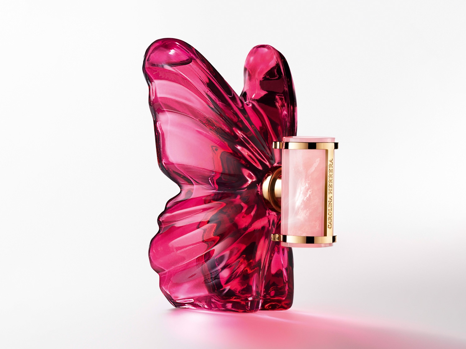 Parfum Carolina Herrera v tvare ružového motýľa s ružovým puzdrom na rúž so zlatými detailmi.