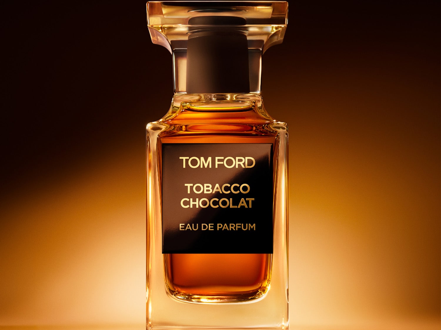 Der Tom Ford Tobacco Chocolat Eau de Parfum Flakon ist ein elegantes, rechteckiges Glasfläschchen mit goldener Flüssigkeit und einem schwarzen Etikett, das den Markennamen und den Duftnamen in Gold zeigt.