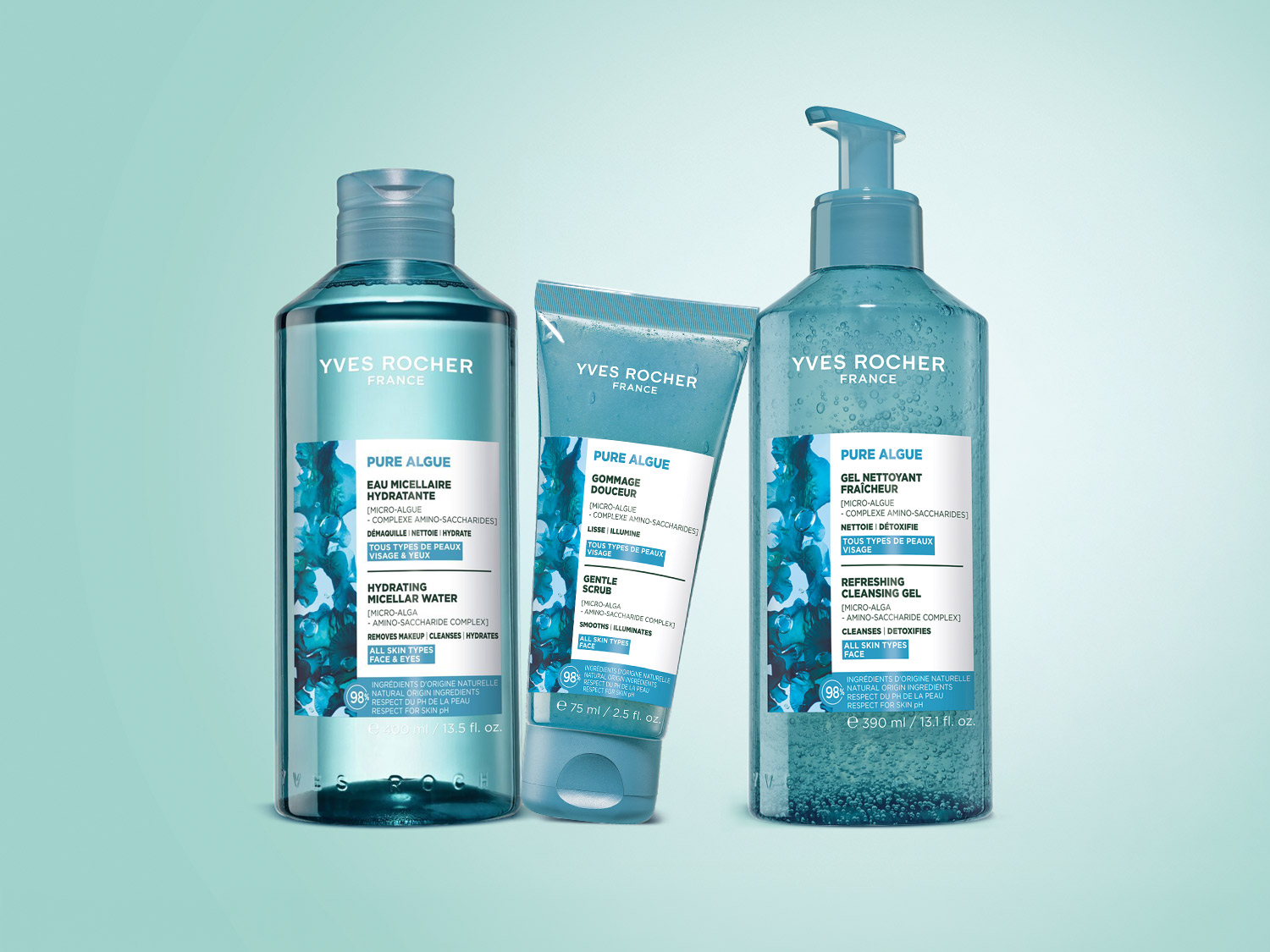 Trzy produkty Yves Rocher Pure Algue, w tym płyn micelarny, peeling i żel oczyszczający, stoją na jasnoniebieskim tle, prezentując swoje eleganckie, przezroczyste butelki z turkusowymi etykietami.