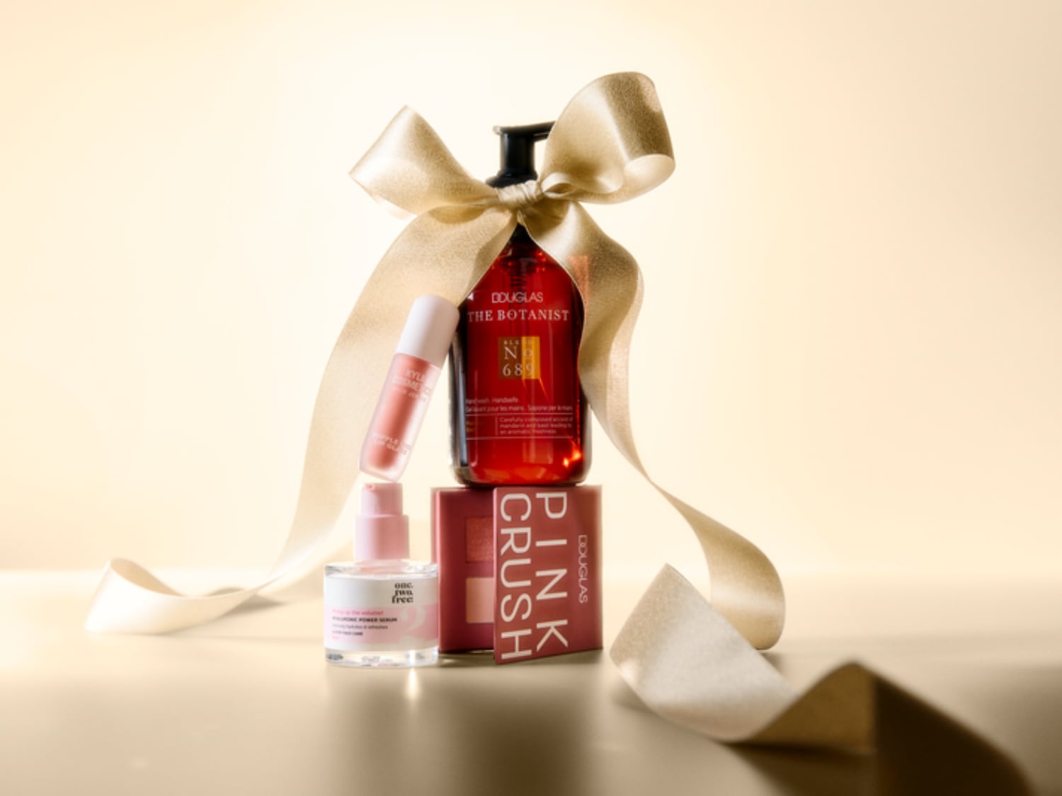 Un coffret cadeau Douglas The Botanist, Pink Crush et un sérum One.Two.Free, joliment emballé avec un ruban doré, parfait pour offrir.