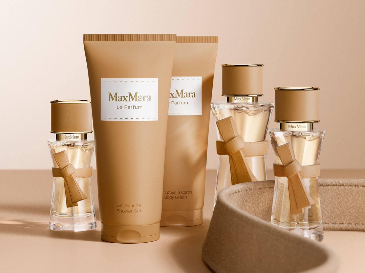 Zestaw Max Mara Le Parfum zawiera żel pod prysznic, balsam do ciała i dwie butelki perfum, wszystkie w eleganckich, beżowych opakowaniach z białymi etykietami.