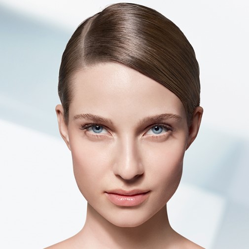 Portret kobiety o jasnej cerze, z niebieskimi oczami i gładko zaczesanymi brązowymi włosami, skierowanej twarzą do przodu.