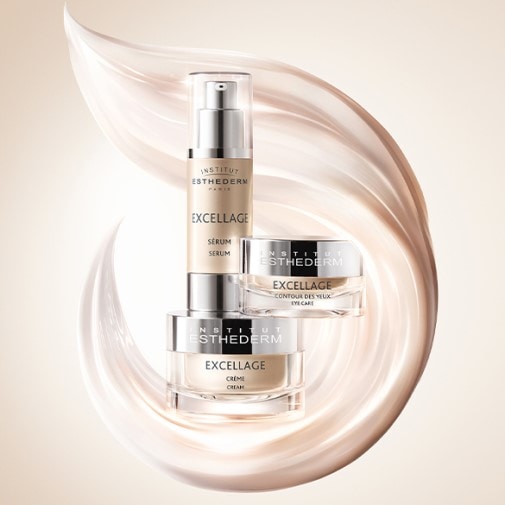 Zestaw kosmetyków Institut Esthederm Excellage w beżowych opakowaniach: serum, krem pod oczy i krem do twarzy, otoczone abstrakcyjną, kremową smugą.