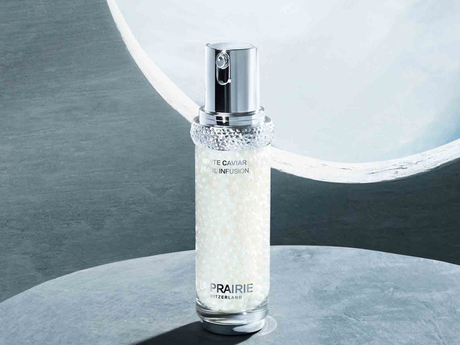 Lahvička La Prairie White Caviar Pearl Infusion obsahuje perličky v průhledném séru, s stříbrným dávkovačem a víčkem, které slibují luxusní péči o pleť.