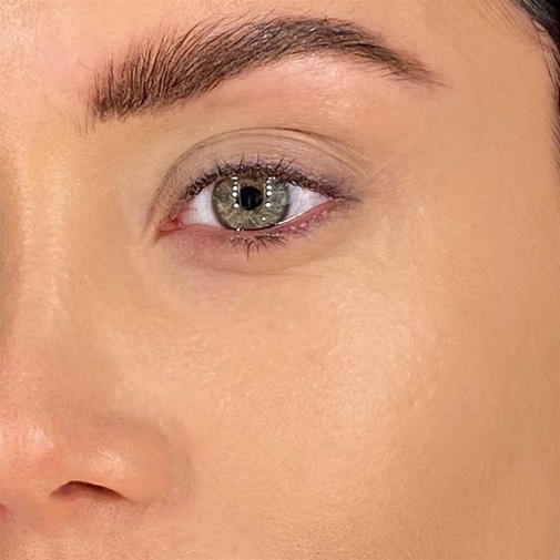 Primo piano del lato destro del viso di una donna con occhi verdi, sopracciglia folte e pelle chiara.