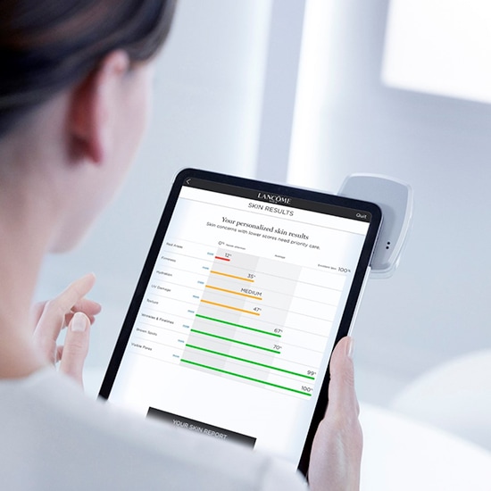 Kobieta przegląda na tablecie wyniki analizy skóry Lancôme, które wskazują na poziom nawilżenia, tekstury i widoczności porów.
