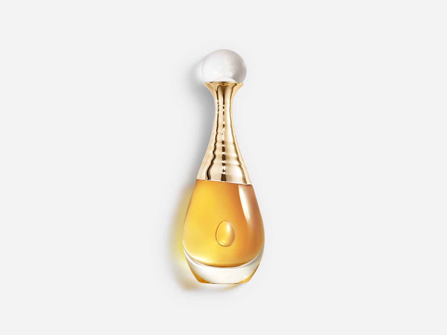 Butelka perfum J’Adore Dior o pojemności 100 ml ma kształt łzy, złoty korek i przezroczystą kulkę na górze, wypełniona jest bursztynowym płynem.