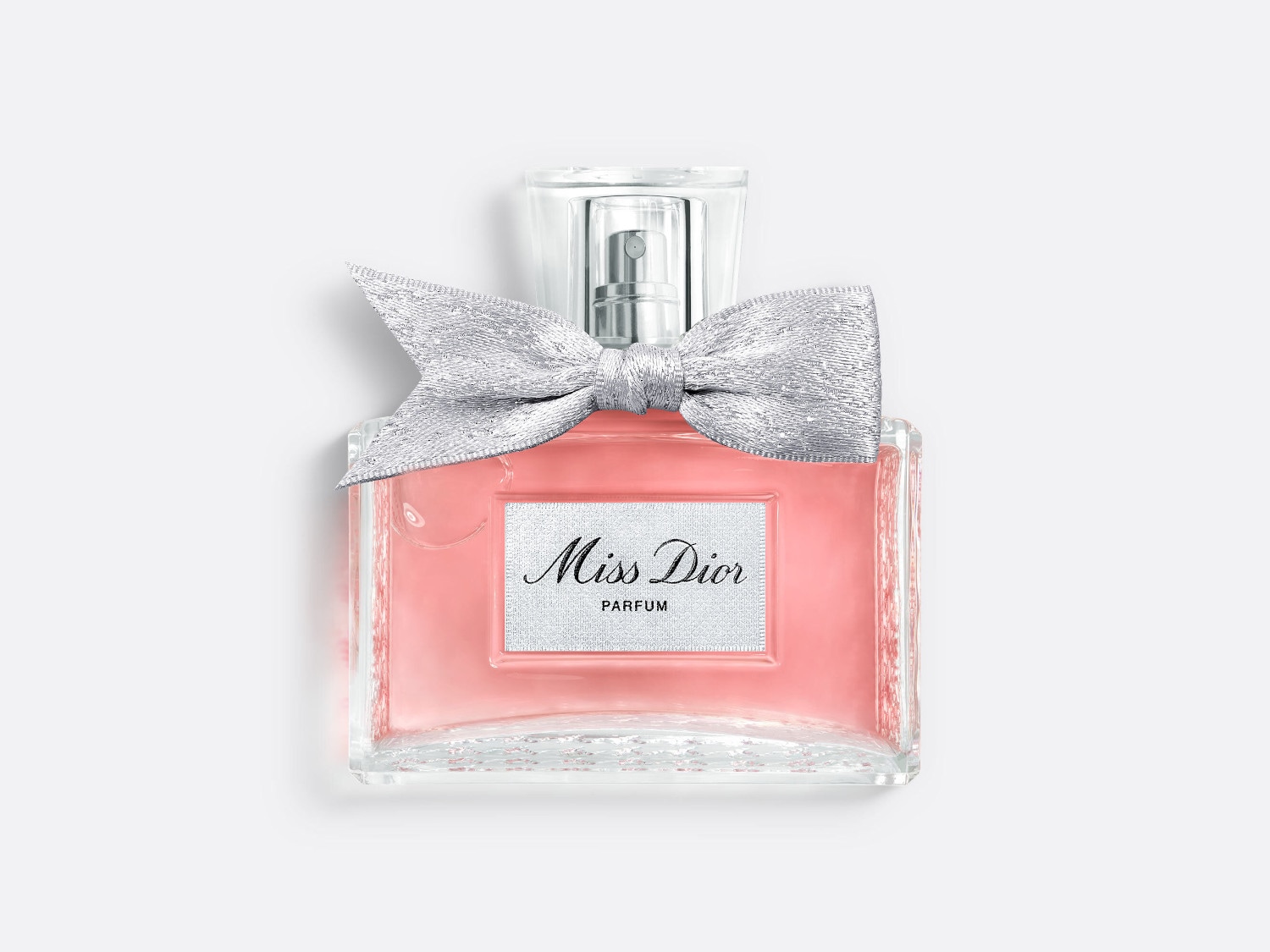 Kwadratowy flakon Miss Dior z różową zawartością, ozdobiony srebrną kokardką, emanuje elegancją i kobiecością.