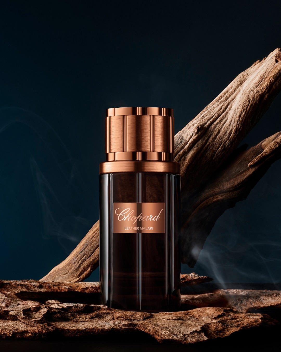 Butelka perfum Chopard Leather Malaki o pojemności 80 ml, z brązową etykietą i korkiem, stoi na tle kawałka drewna.