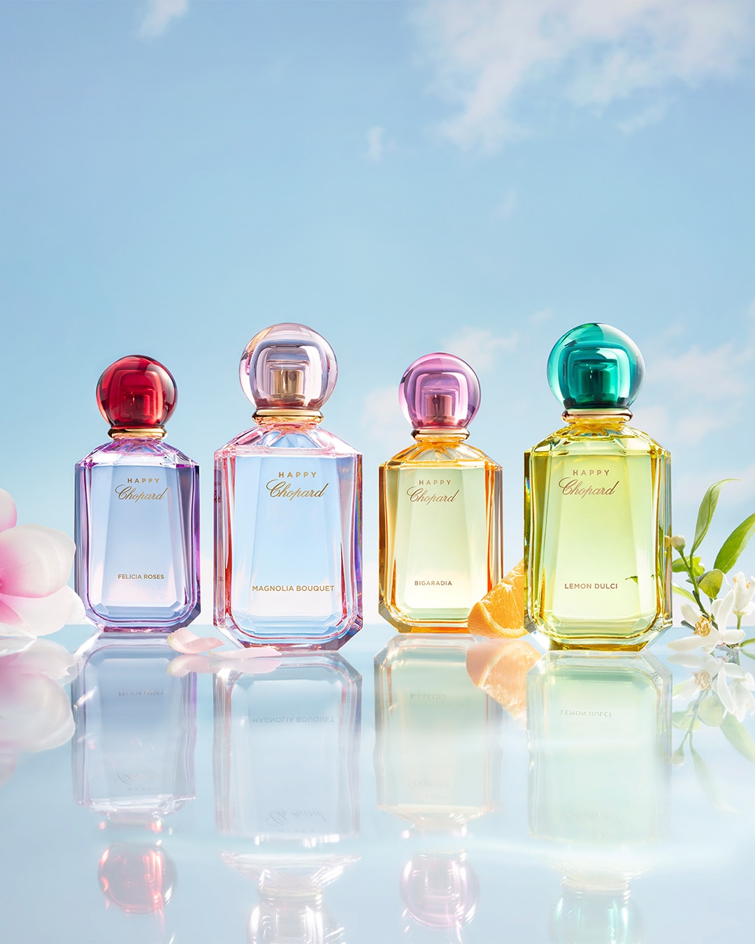 Cztery flakony perfum Chopard Happy z kolorowymi korkami (czerwony, różowy, pomarańczowy i zielony) stoją obok siebie, każdy z nazwą zapachu: Felicia Roses, Magnolia Bouquet, Bigaradia i Lemon Dulci.