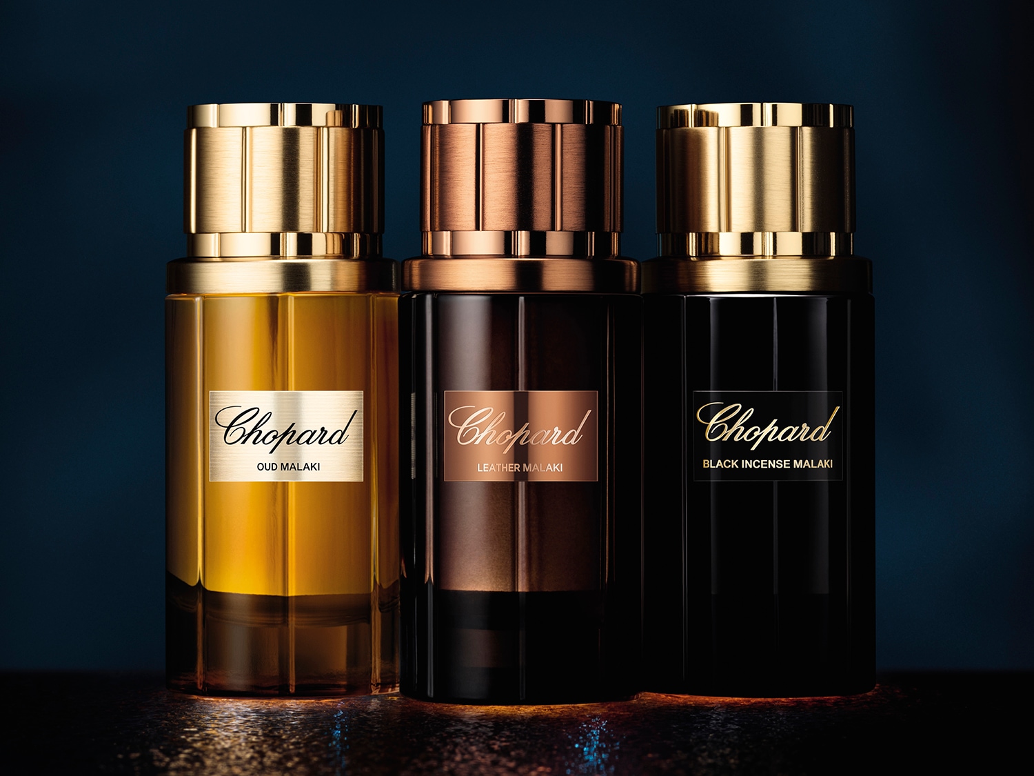 Trzy flakony perfum Chopard Malaki: Oud w złotym flakonie, Leather w brązowym i Black Incense w czarnym, każdy z metalową nakrętką.