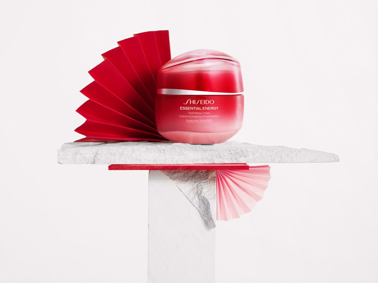 De Shiseido Essential Energy Hydrating Cream in een rode verpakking, gepresenteerd met rode decoratieve elementen, belooft een intensieve hydratatie met hyaluronzuur.