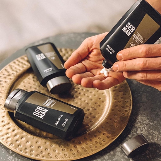 Na złotym talerzu leż ą trzy czarne butelki Seb Man, a z jednej z nich wyciskany jest biały krem na dłoń.