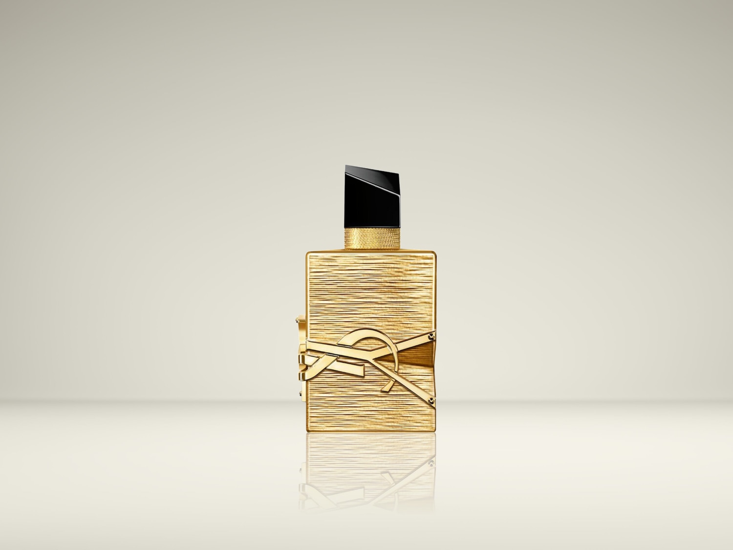 De YSL Libre Le Parfum is een vierkante, goudkleurige parfumfles met een geribbeld patroon en een zwart-gouden dop, versierd met het goudkleurige YSL-logo.