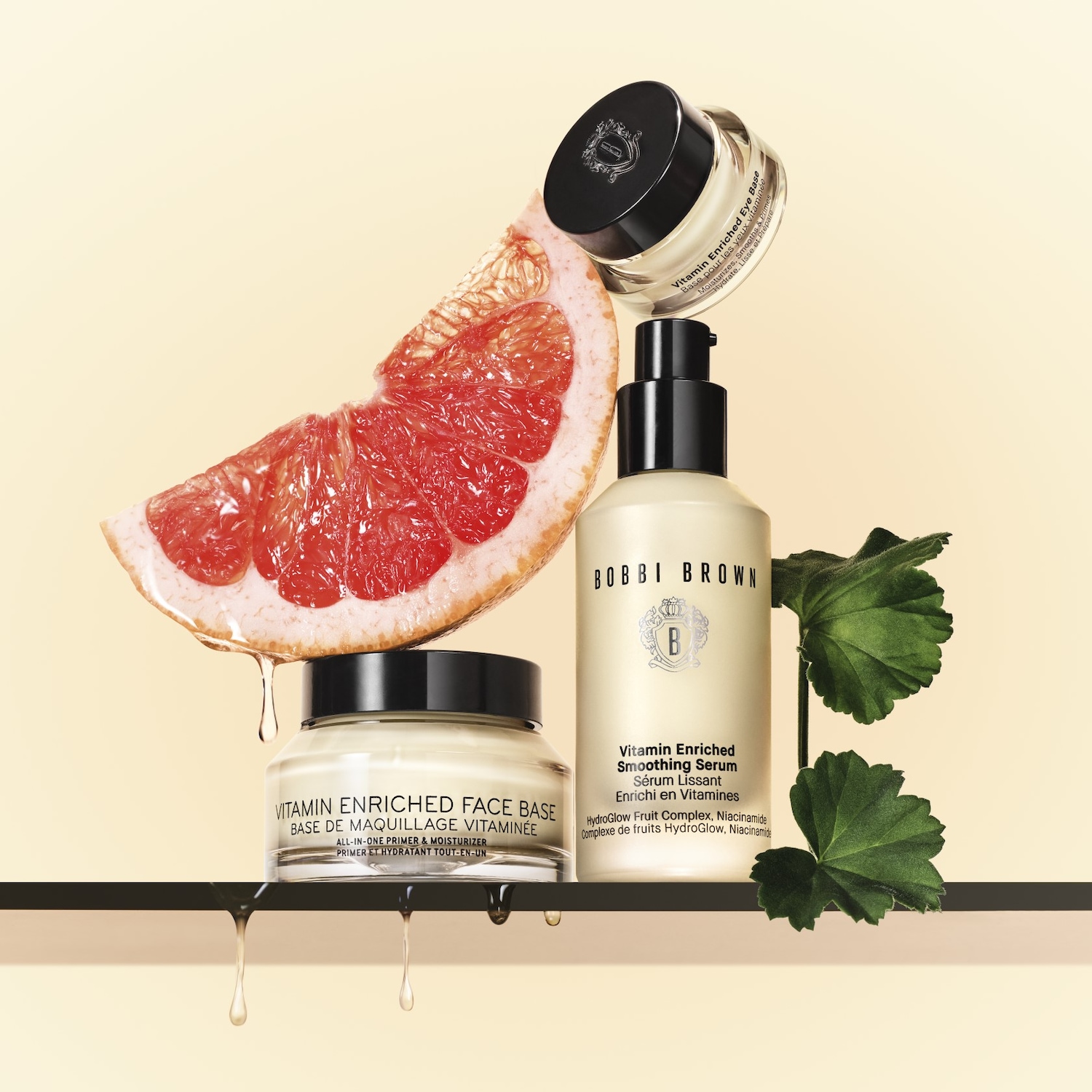 A Bobbi Brown Vitaminokkal dúsított arcbázis, a Vitaminokkal dúsított simító szérum és a Vitaminokkal dúsított szemalapozó egy piros grapefruit szelettel és zöld levelekkel van bemutatva.