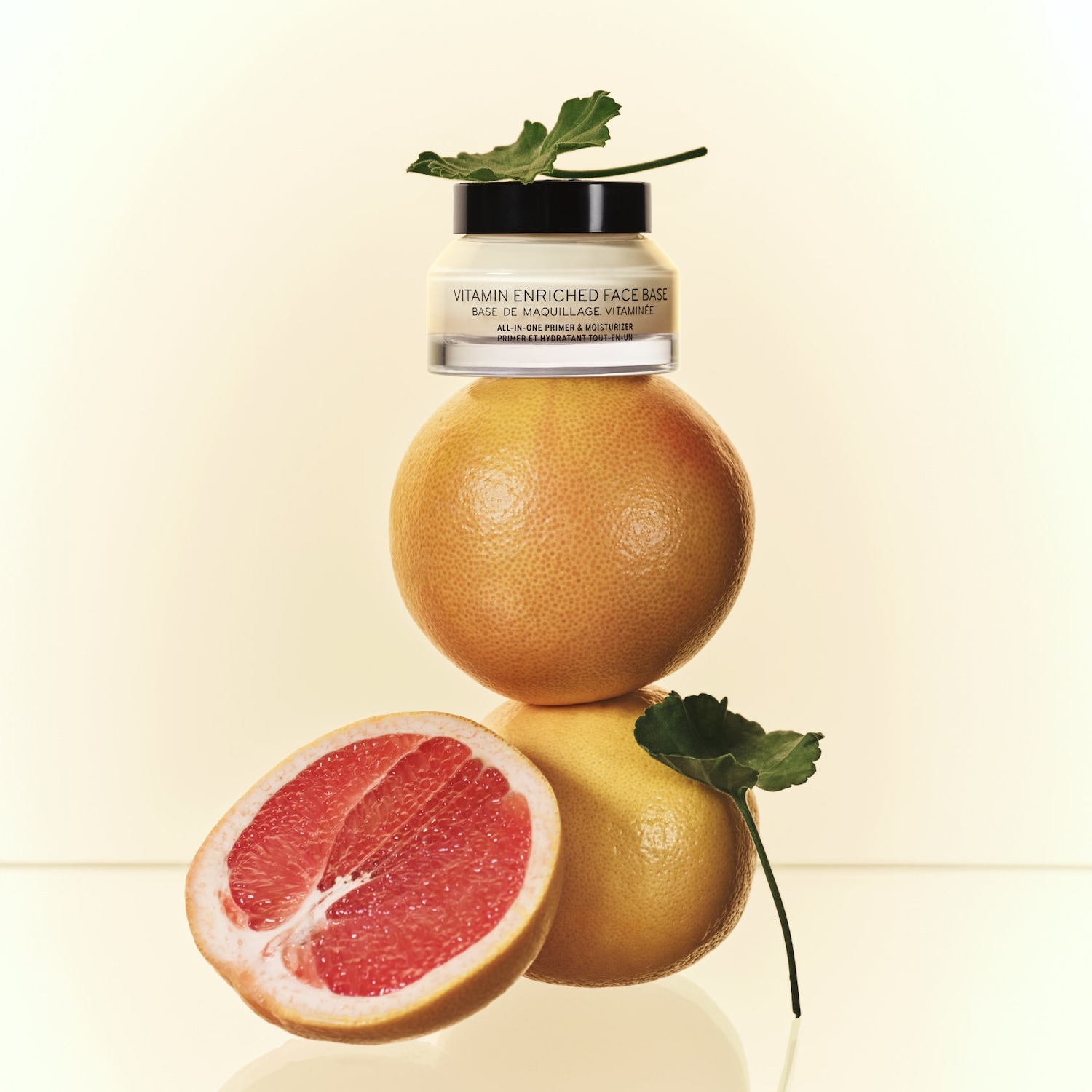 A Vitamin Enriched Face Base egy grapefruit kupacon pihen, melynek felvágott fele is látható, kiemelve a termék frissességét és természetességét.