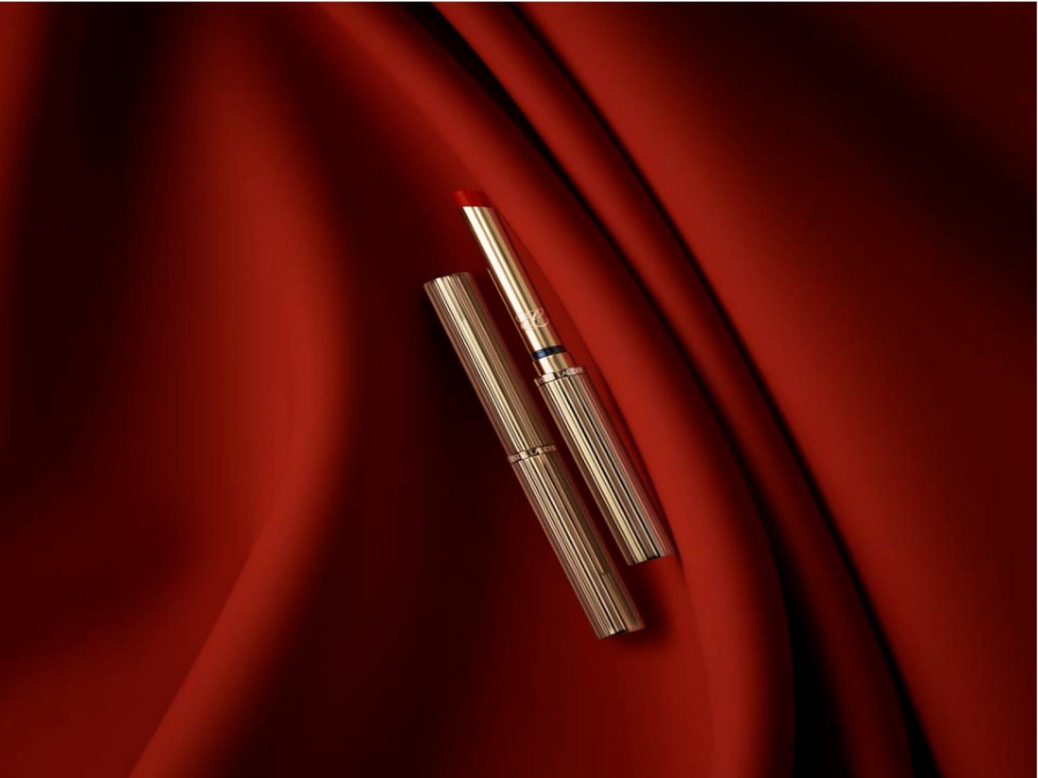 Szminka w złotym opakowaniu na czerwonym tle, idealna do podkreślenia ust i dodania elegancji.