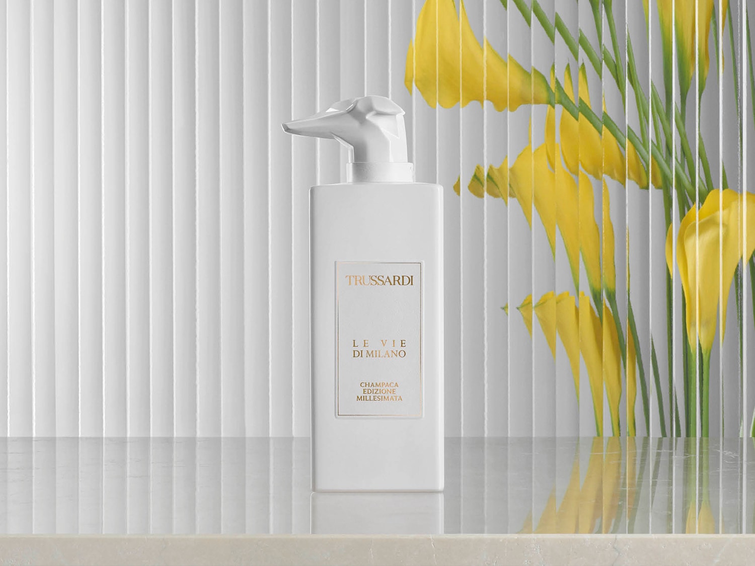 Biała butelka Trussardi Le Vie di Milano Champaca Edizione Millesimata z dozownikiem w kształcie głowy psa na tle żółtych kwiatów.