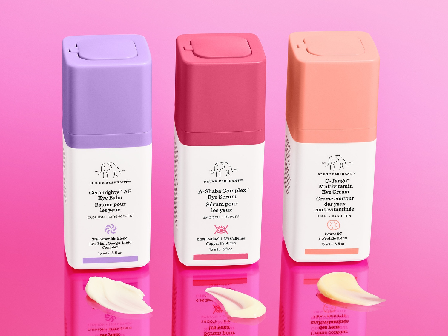 Drie Drunk Elephant oogcrèmes in paarse, roze en perzikkleurige verpakkingen, elk met een crème swatch eronder, voor een verzorgde en stralende oogopslag.