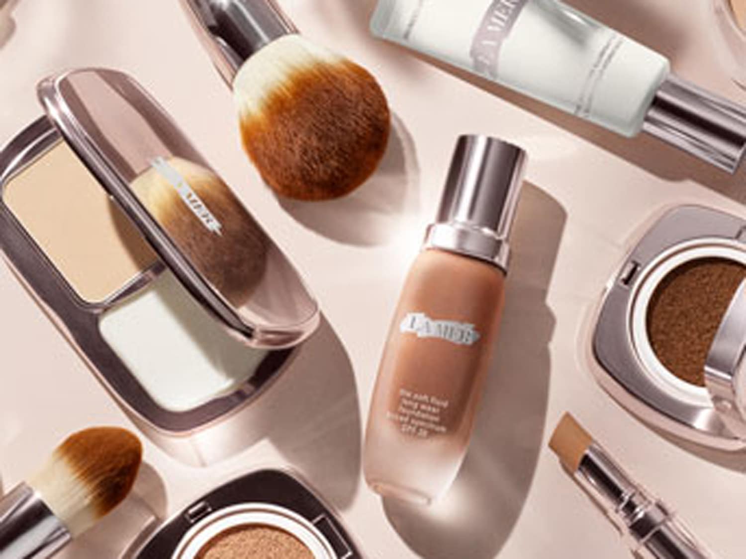 Een verzameling La Mer make-up producten, waaronder foundation, poeder en concealer, samen met make-up borstels.