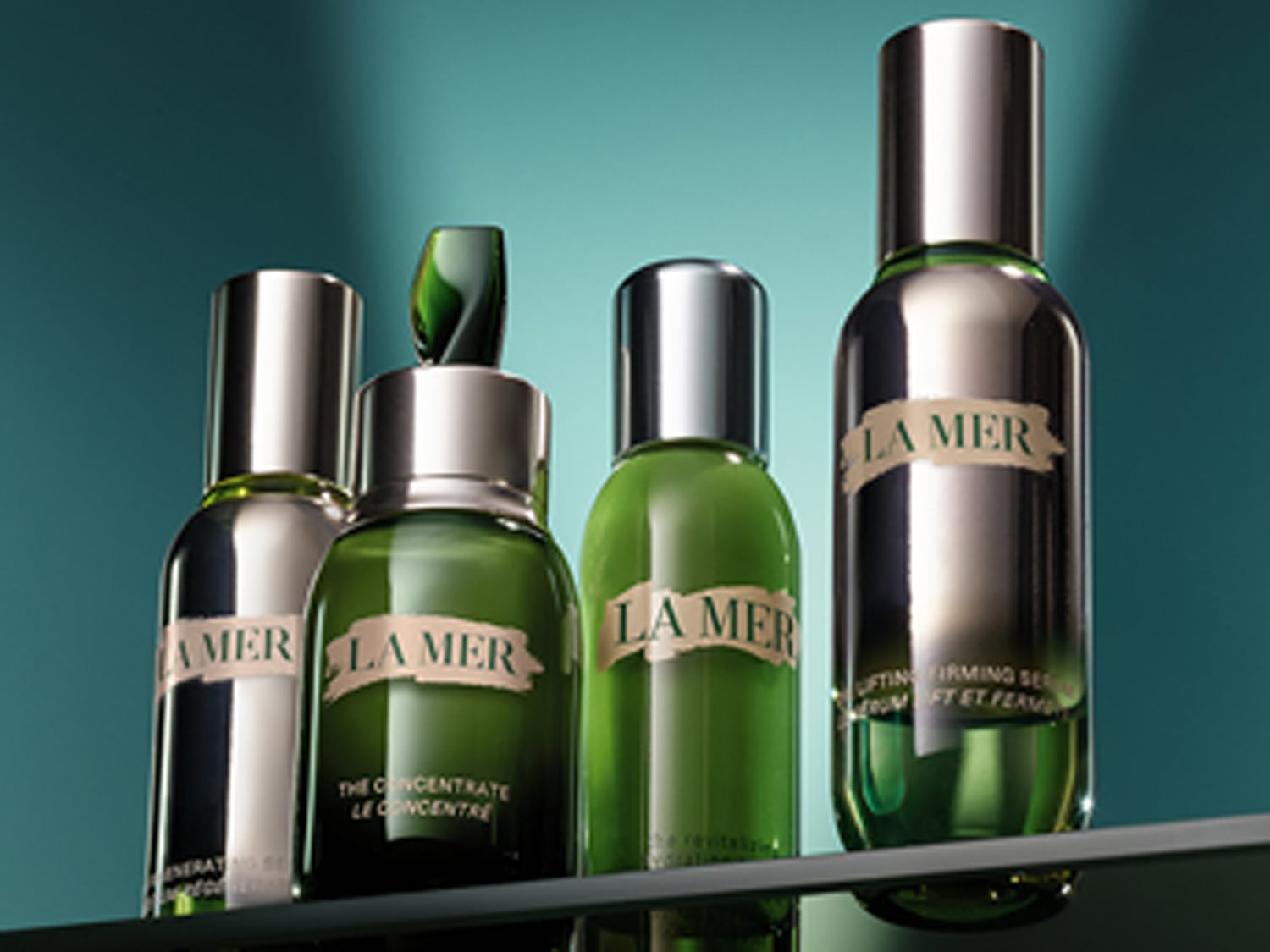 Verschillende flessen La Mer huidverzorgingsproducten staan op een rij, met zilveren doppen en groene tinten die de luxe en verjongende eigenschappen van de collectie benadrukken.
