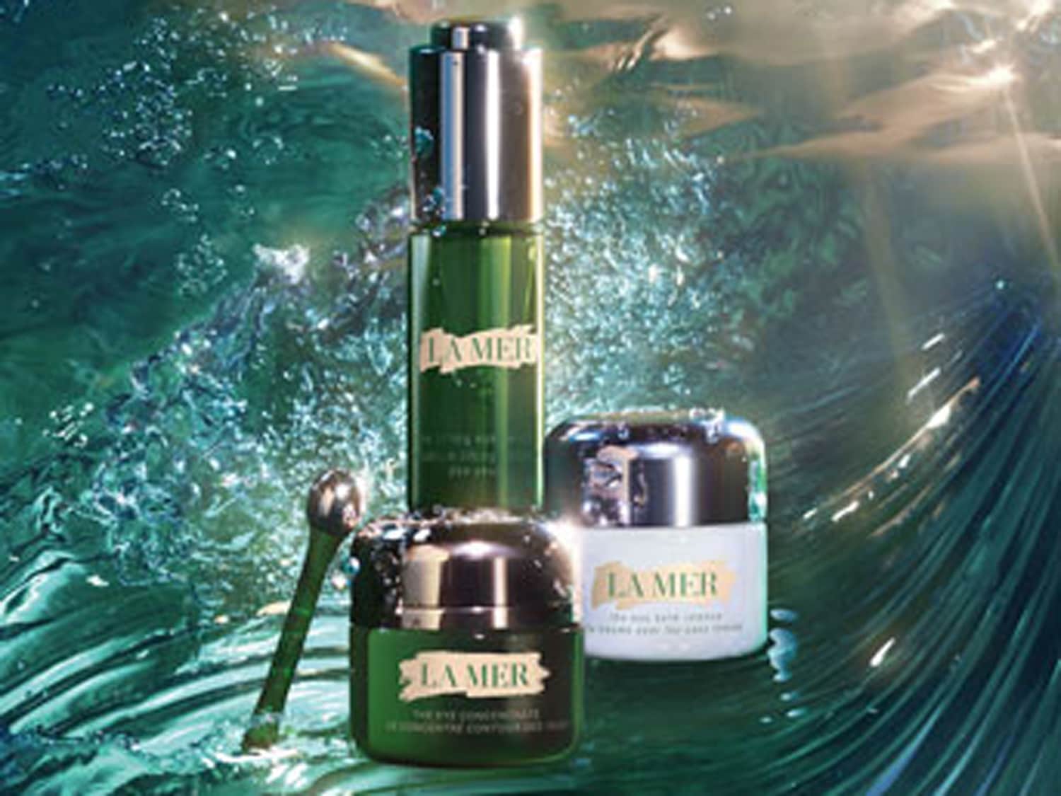 La Mer huidverzorgingsproducten, waaronder een groen serum, een oogconcentraat met een zilveren applicator en een witte crème, staan klaar om je huid te verwennen.