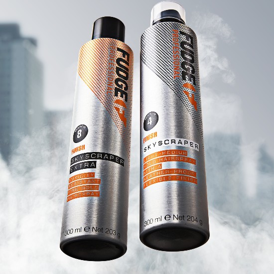 Dwa srebrne aerozole do włosów Fudge Professional Skyscraper: jeden w wersji Extra z pomarańczowymi akcentami, drugi w wersji Light-Medium z szarymi akcentami, oba o pojemności 300 ml.