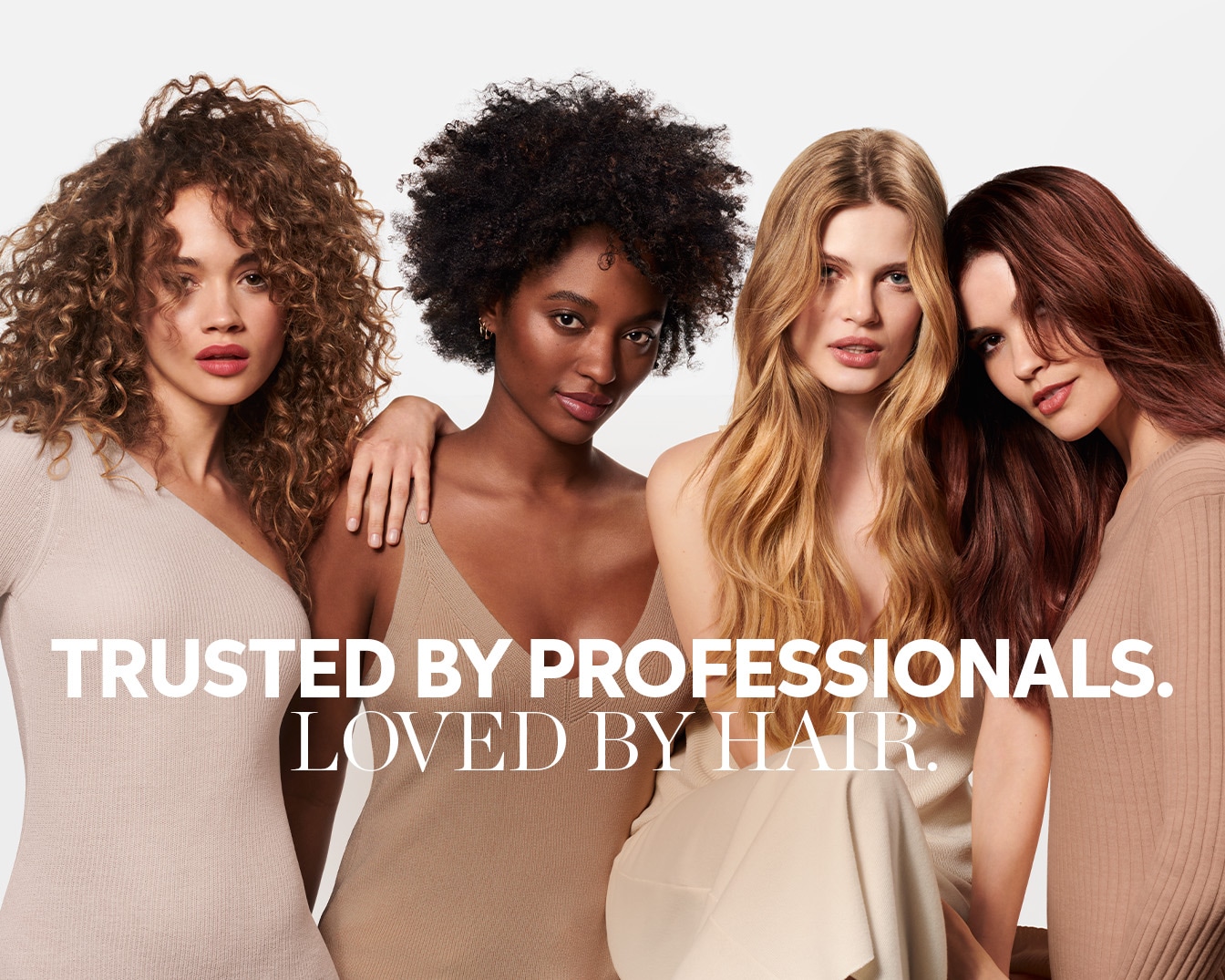 Cztery kobiety o różnej karnacji i typach włosów, ubrane w beżowe ubrania, prezentują się na tle hasła: „Zaufane przez profesjonalistów, uwielbiane przez włosy”.