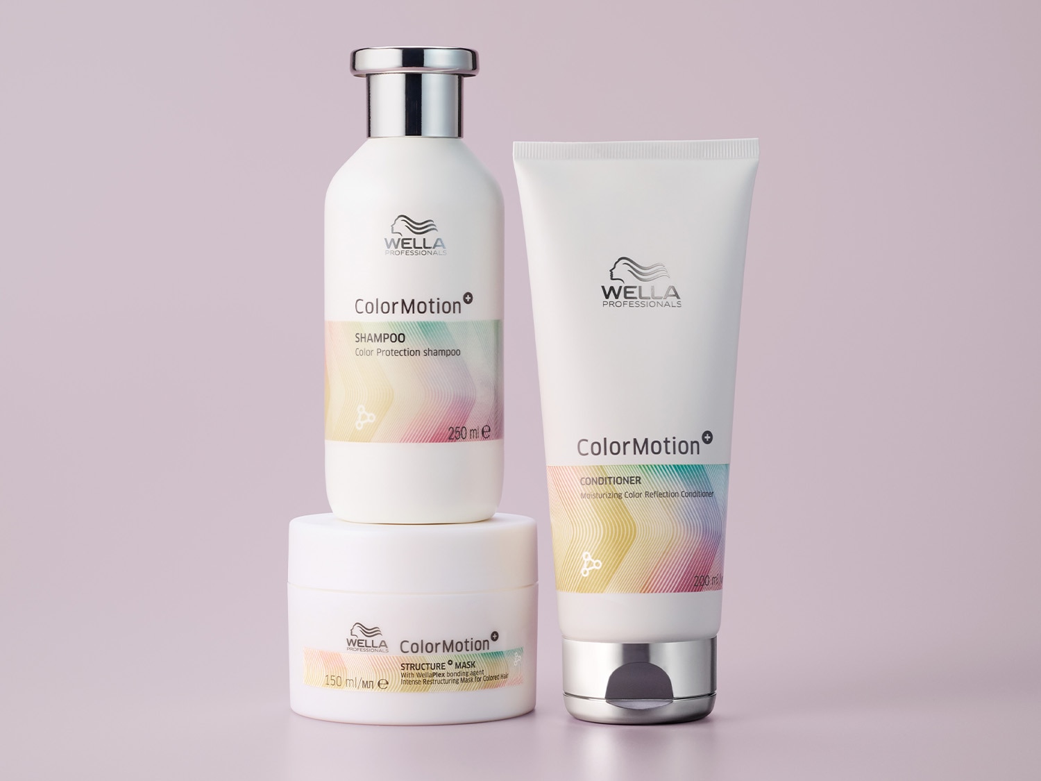 Na fioletowym tle znajdują się trzy białe opakowania produktów do włosów Wella Professionals ColorMotion: szampon w butelce, odżywka w tubie i maska w słoiczku, wszystkie z kolorowymi akcentami.