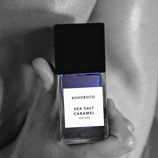Na dłoni trzymany jest flakon perfum Bohoboco Sea Salt Caramel z czarną nakrętką i etykietą z nazwą.