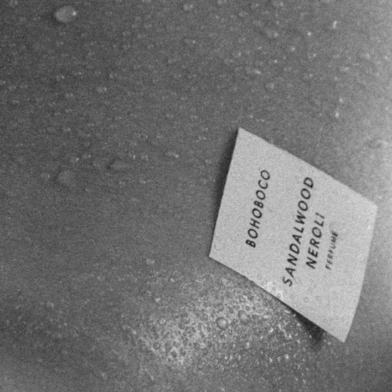 Czarno-białe zdjęcie próbki perfum Bohoboco Sandalwood Neroli leżącej na mokrej powierzchni, prezentujące minimalistyczny design i subtelne połączenie zapachowe.
