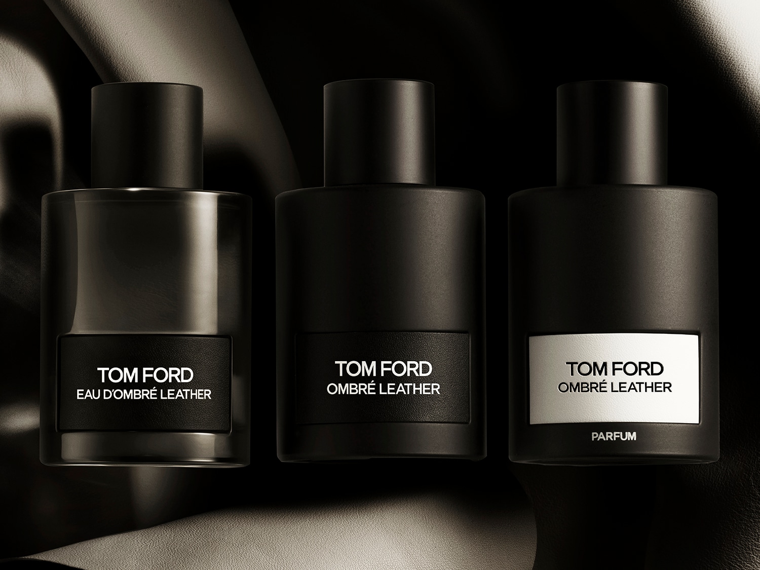 Drie zwarte Tom Ford parfumflessen staan op een rij, elk met een ander label: Eau d'Ombré Leather, Ombré Leather en Ombré Leather Parfum.