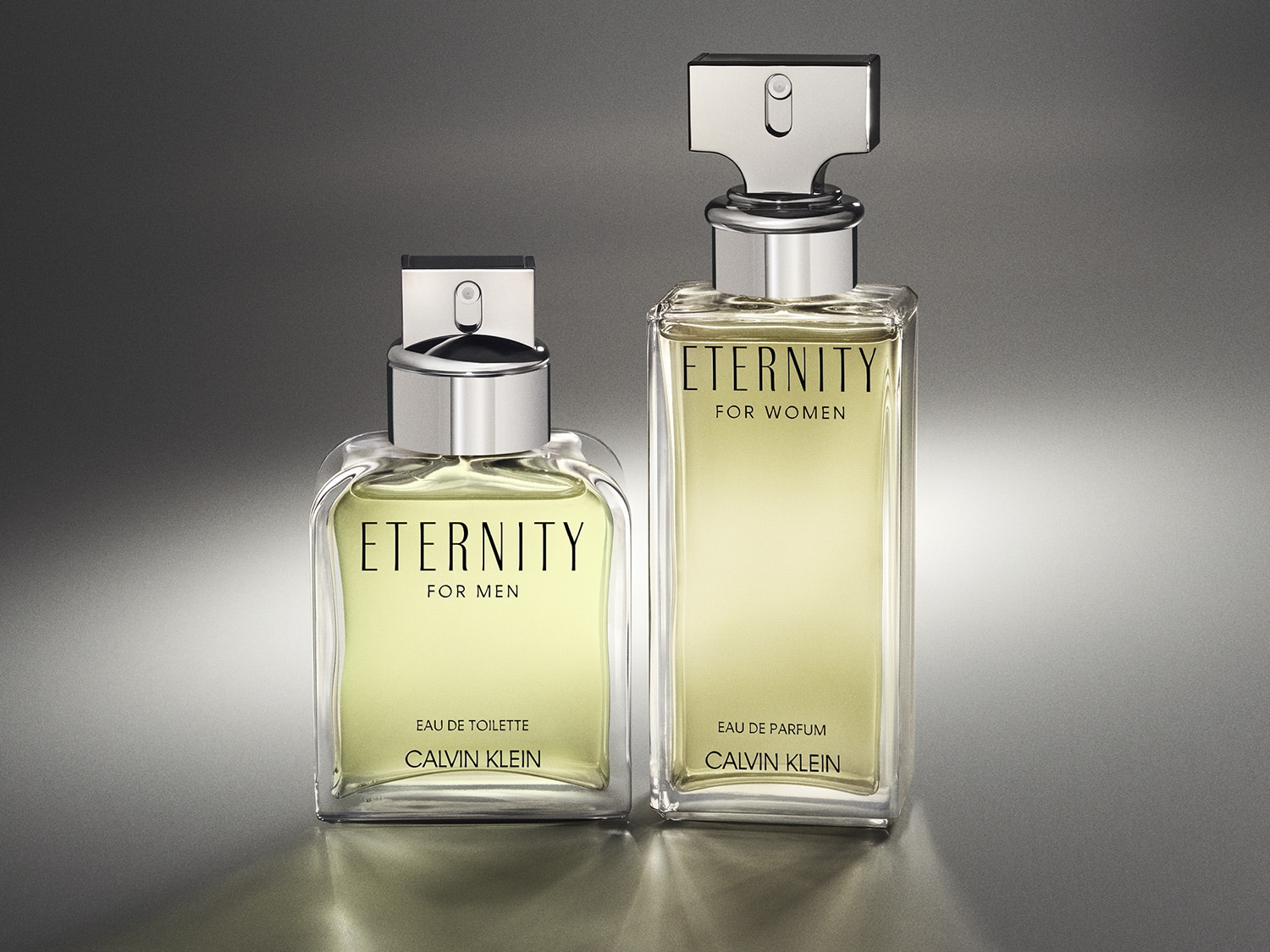 Dva flakony parfému Calvin Klein Eternity pro muže a pro ženy, pánský má světle zelenou tekutinu a dámský má světle žlutou tekutinu.