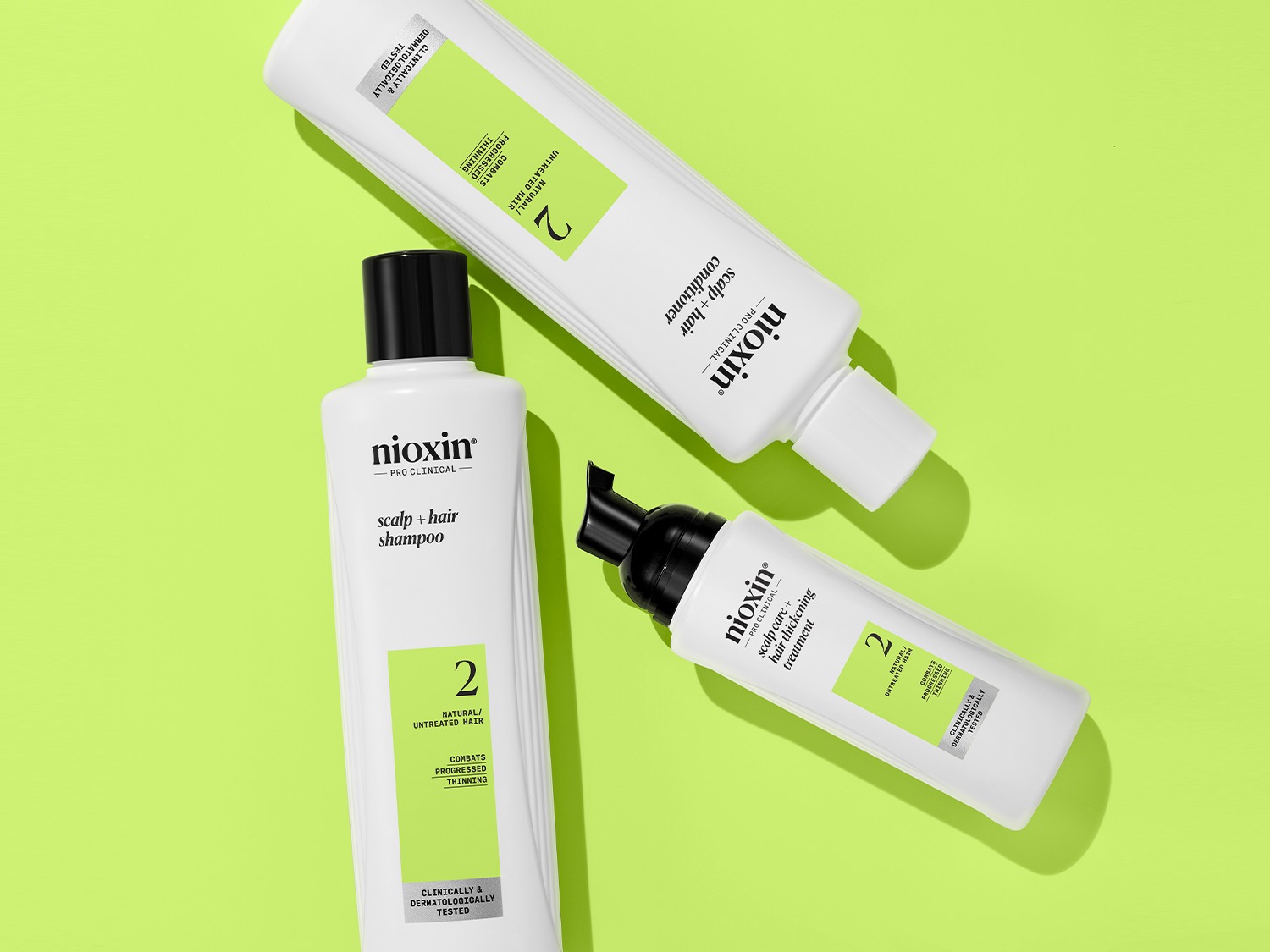 Three white Nioxin bottles, including scalp and hair shampoo, conditioner, and hair thickening treatment, are designed for natural or untreated hair to combat progressed thinning.