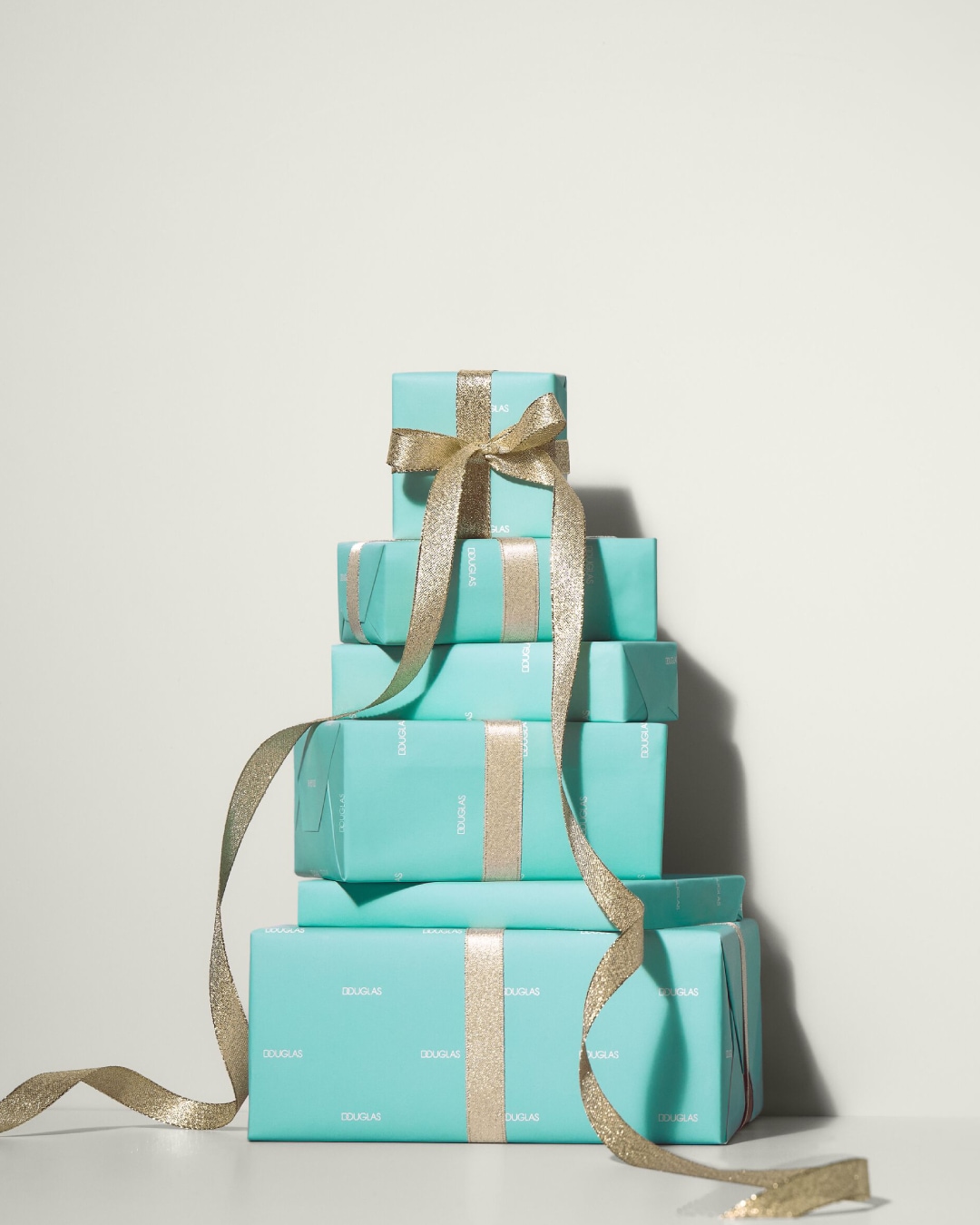 Wieża prezentów Douglas w turkusowym papierze i złotych wstążkach, idealna na każdą okazję.