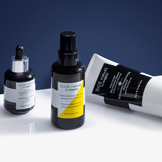 Zestaw do pielęgnacji włosów Hair Rituel by Sisley zawiera olejek, serum i szampon w czarno-białych opakowaniach, zapewniające kompleksową pielęgnację włosów i skóry głowy.