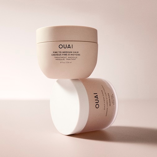 Zwei hellrosa Tiegel von OUAI stehen übereinander, der obere ist eine Haarmaske für feines bis mittelfeines Haar, der untere ein Kopfhaut- und Körperpeeling.