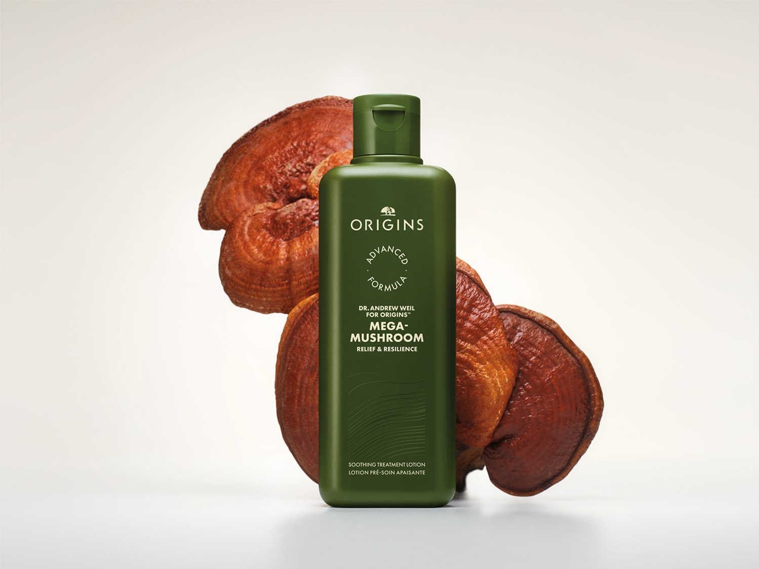Een groene fles Origins Mega-Mushroom Relief & Resilience Soothing Treatment Lotion staat voor twee grote, roodbruine paddenstoelen.