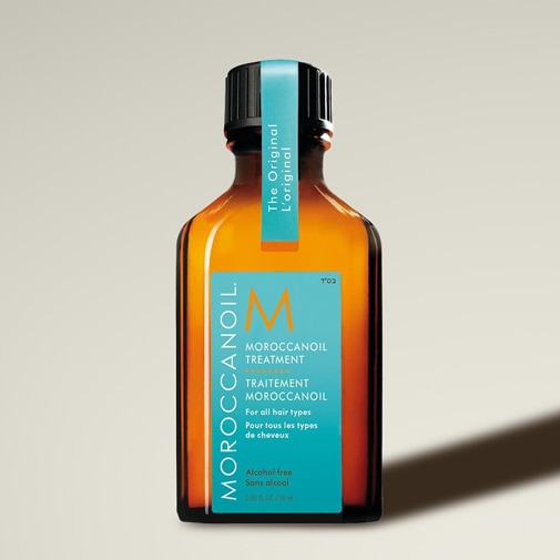 Das Moroccanoil Treatment kommt in einer bernsteinfarbenen Glasflasche mit einem türkisfarbenen Etikett, das die Aufschrift „The Original L'original“ trägt und für alle Haartypen geeignet ist.
