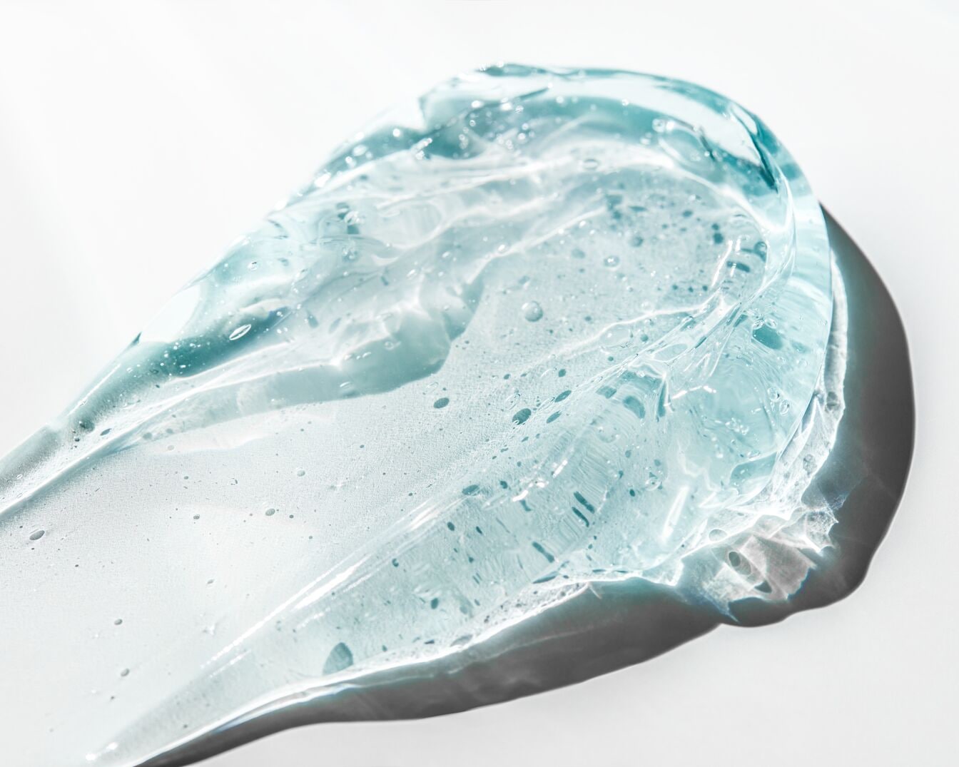 Primer plano de un gel transparente azulado con burbujas, mostrando su textura brillante e hidratante.