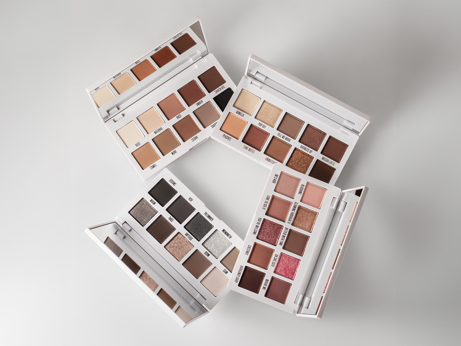 Cztery palety cieni do powiek w białych opakowaniach, każda z różnymi odcieniami, od neutralnych po ciemne, z nazwami takimi jak Vanilla, Mocha Latte i Burgundy Baby.