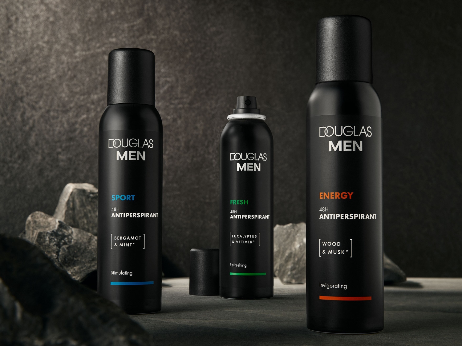 Trzy czarne dezodoranty w sprayu Douglas Men, każdy z napisem „48H Antiperspirant” i różnymi zapachami: Sport (bergamotka i mięta), Fresh (eukaliptus i wetiwer) oraz Energy (drewno i piżmo).